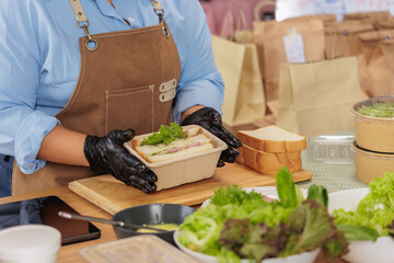 Chef preparing fresh meal with greens and bread in a kitchen. Healthy takeout food packaging. Culinary skills and organic ingredients.