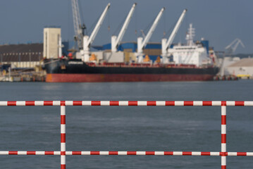 SEA PORT IN GDYNIA - Safety railing on the quay and loading of a bulk carrier in the Baltic Grain...