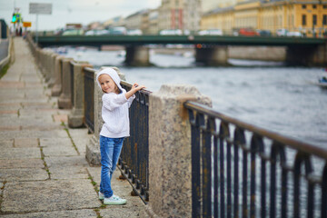 Adorable preschooler girl walking on the Fontanka river embankment in St. Peterburg, Russia.