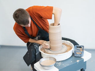 A potter works on a potter's wheel to smooth the surface of a vase.