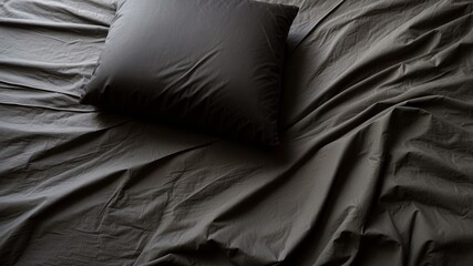 Minimalist black pillow on wrinkled sheets