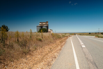 Discover the tranquil charm of rural landscapes with this image of an empty road leading to a lone,...
