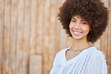 A curly-haired woman smiles and wears a white shirt