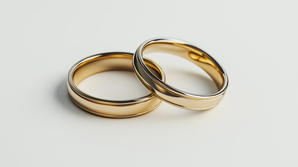 Two golden wedding rings resting on white surface