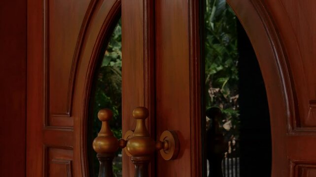 The hand of a young Asian man or woman is knocking on a wooden door. close up of a hand knocking on the door from outside the house or outside the street.