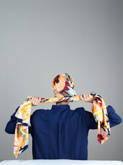 Naklejka premium Hijab, scarf and back of woman in studio for islamic fashion, arabic culture and modest clothes. Raya, eid Mubarak celebration and elegance with muslim person on grey background for oriental design