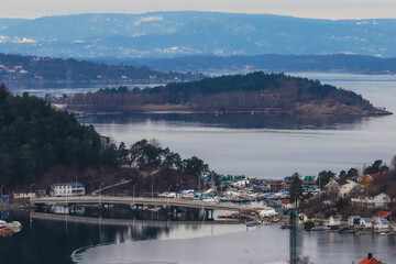 A serene view of the coastal landscape in Norway showcasing islands, boats, and calm waters on a tranquil day