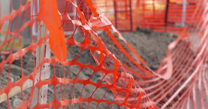 Protective orange mesh fencing at a construction area, capturing the details of safety precautions on a city street. Close-up footage.