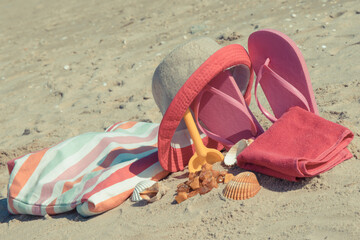 Different accessories for relax on sand. Straw hat, slippers and towel. Summer time on beach