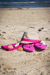 Straw hat, slippers and towel on sand at beach. Accessories for relax in summer