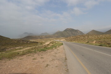 street with distant mountains , cloudy sky and some grass