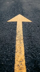 Yellow arrow painted on dark asphalt road surface pointing forward, symbolizing direction, guidance, and progress in journey or life choices.