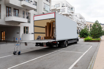 White delivery truck with tailgate open in front of modern residential buildings. Copy space.