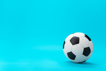 Naklejka premium Photo of white and black soccer ball as football concept with copy space. Minimalist image of leather football ball over blue turquoise background with right side composition.