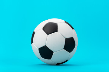 Fototapeta premium Photo of white and black soccer ball as football concept. Minimalist image of leather football ball over blue turquoise background with central composition.