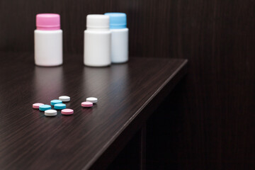 Colorful vitamin pills on brown table with vitamin drug bottles in the background.