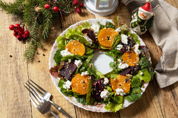 Christmas appetizer New year meal idea. Christmas wreath salad with beetroot, tangerines, feta cheese and pecans on the rustic table.