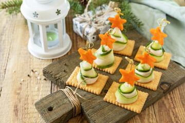 New year meal idea Creative appetizers christmas. Christmas trees of ham, cucumber, cheese and star of carrot on crackers on the rustic table.