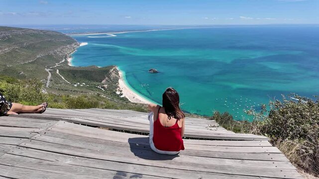 Panoramic shot from Miradouro do Portinho da Arr&aacute;bida, showing beaches, Set&uacute;bal, Troia, and the Sado River estuary against a vibrant seascape.
