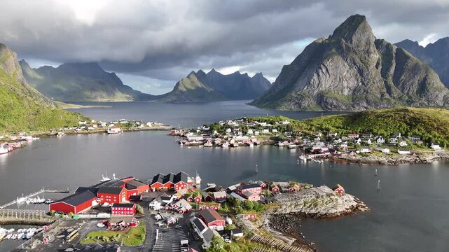 Aerial view of the bridges and towns in Reinefjorden with foggy rainbow background, in Norway - pan, drone shot in 4K. Reine, Reinebringen, Lofoten, Hamnoy.