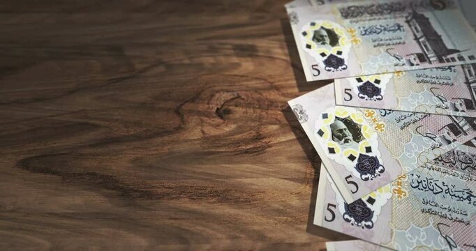 Libya dinar 5 LYD banknotes on the wooden table. Libyan currency paper notes 3D concept background. Seamless and looped.