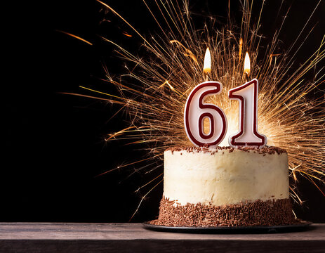 Birthday cake with 61 year old birthday candle on dark background with bokeh and sparklers. Copy space