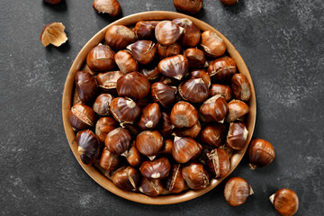 Delicious roasted edible chestnuts on a metal plate, top view