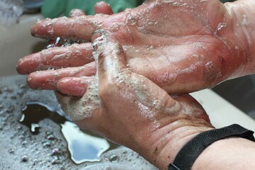 Fototapeta premium man washing dirty hands at sink with soap lather