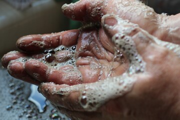 man washing dirty hands at sink with soap lather