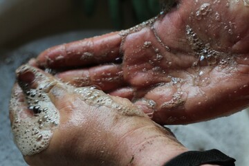 man washing dirty hands at sink with soap lather