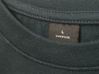 Close up of black t-shirt's round neck collar. Size L oversize t-shirt label tag. Mock up for...