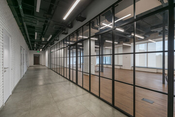 An open space of a modern office with panoramic windows and glass partitions. The room is decorated in loft style.