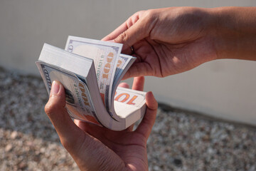 close up of a woman's hand holding a lot of 100 dollar bills. counting 100 dollar bills