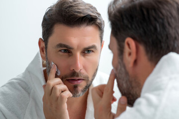 Beauty man applying cosmetic cream on face. Facial treatment. Beauty portrait of man applying face cream. Skin care product. Moisturizing creme for wrinkle man face skin. Man with perfect skin.