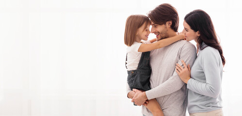 Happy Family. Portrait of millennial parents and their pretty little daughter standing against...