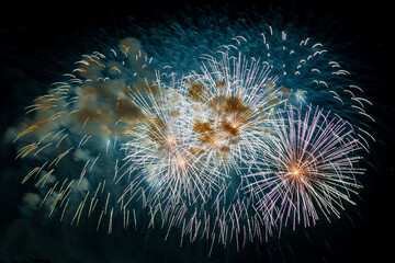 Fototapeta premium Multicolored figures silver and blue bright sparks of fireworks on the black sky. Horizontal photo.