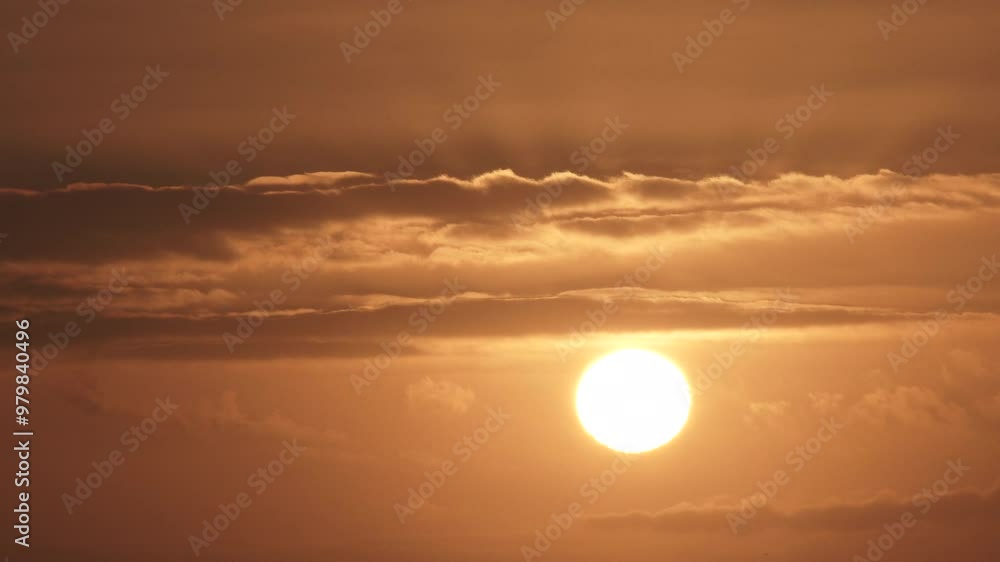 Wall mural fast and falling sun sets behind layers of clouds on a warm summer sky, time lapse.