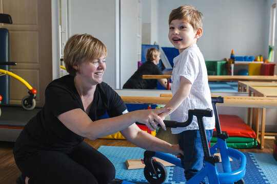 Bobath therapist assists a young boy with cerebral palsy as he practices using a supportive mobility device during a session