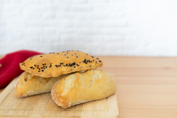 three pieces of bread with sesame seeds on top are on a wooden table.