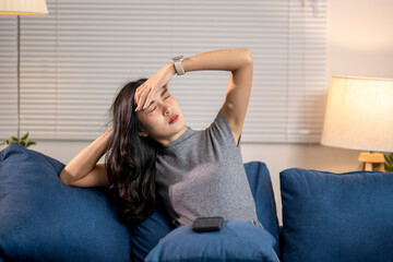 Young woman suffering from strong headache while relaxing on sofa at home