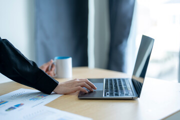 Businesswoman analyzing financial data on laptop in modern office