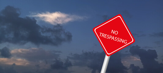 No trespassing sing hanged on an wire fence in front of a dockyard. It says that passing from here is forbidden.