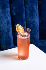 An alcoholic cocktail in a highball collins glass garnished with physalis served with ice