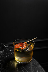 An alcoholic cocktail in a lowball rocks glass served on ice garnished with a lollypop