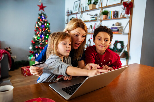 Mom and kids doing Christmas online shopping with laptop and credit card
