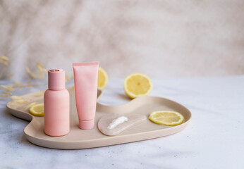 Vitamin C face cream and tonic  with lemon slices on shadows background 