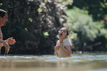 Two friends sharing a fun moment in a cool, refreshing river. The outdoor scene exudes joy and connection during a leisurely summer day.