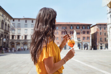 Beautiful young woman drinking aperol spritz  in Italy 