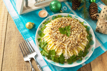 Christmas appetizer New year meal idea. Christmas New Year salad with potatoes, liver and nuts on rustic table.