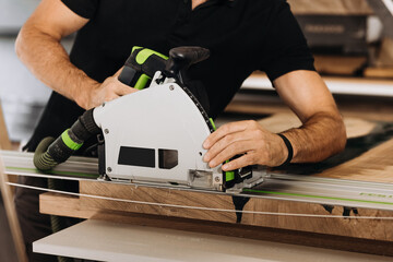 Unrecognizable man working with professional, electric circular saw, making a precise cut along the...
